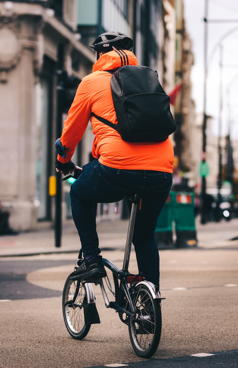 man in orange jacket riding bicycle during daytime